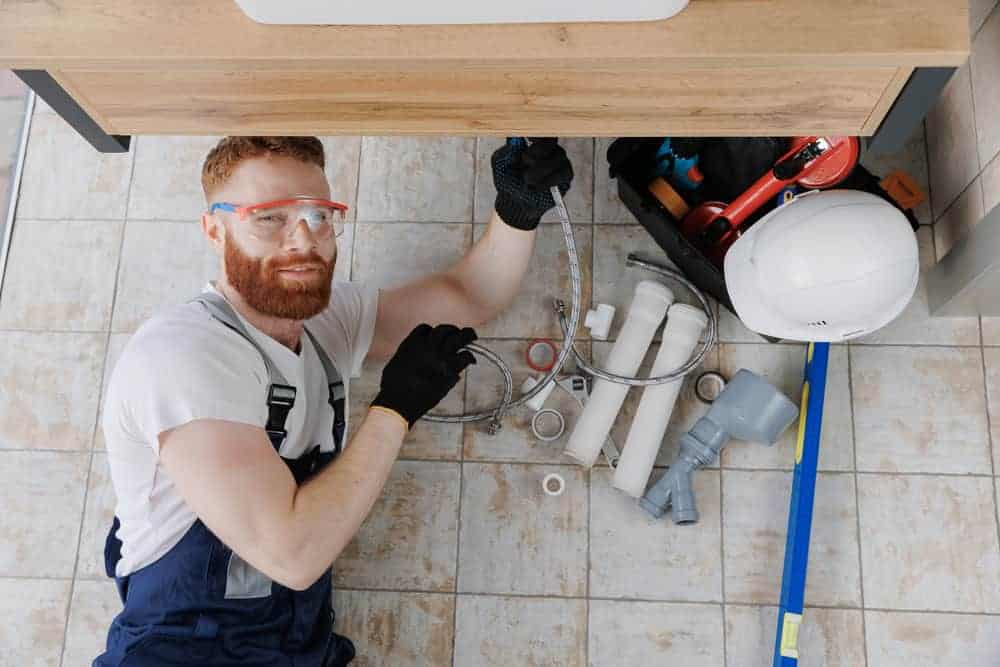 Plumber fixing pipe during emergency plumbing service in a home.